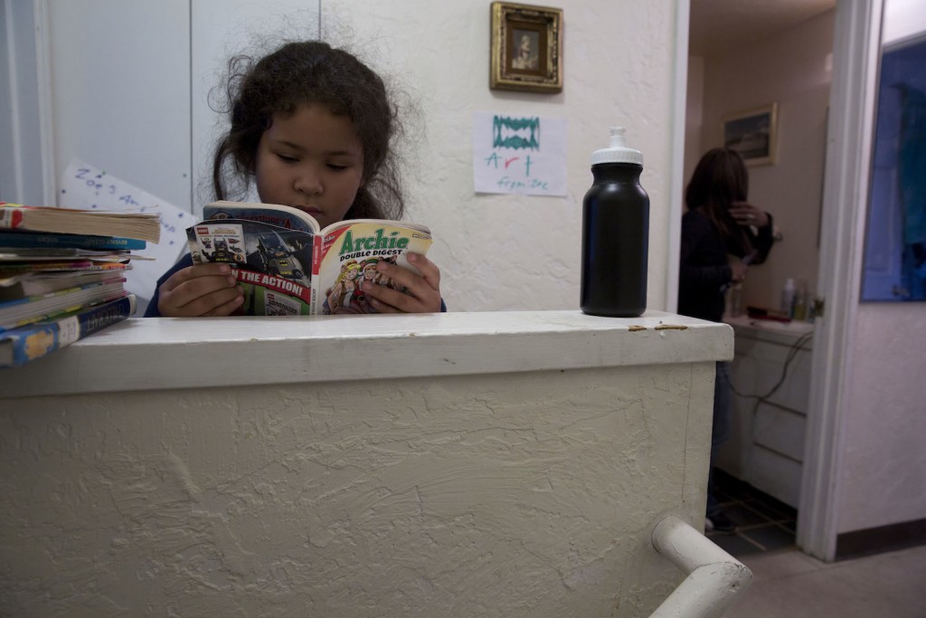 An avid reader, Zoe spends a few moments with a comic book while her mom prepares to walk her to school.